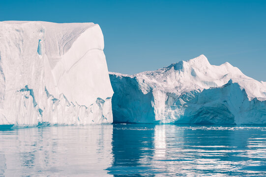 Big icebergs in Atlantic ocean, Ilulissat icefjord, western Greenland. Blue sea and the blue sky at sunny day.