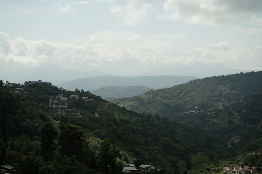 View of rolling green hills and scattered buildings on the slopes in Nagaland, India.