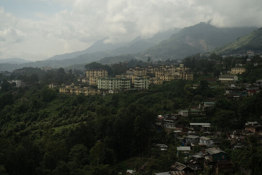 View of residential buildings nestled among lush green hills and mountains in Nagaland, India.