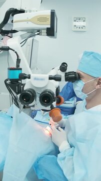 Professional ophthalmologist performing cataract removal and intraocular lens (IOL) implantation under a surgical microscope in an operating room.