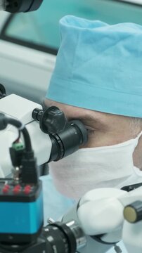 Professional ophthalmologist performing cataract removal and intraocular lens (IOL) implantation under a surgical microscope in an operating room.