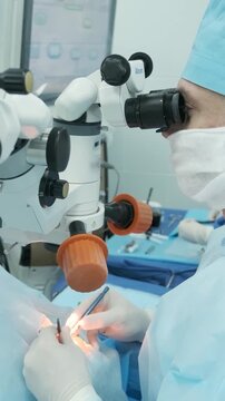 Professional ophthalmologist performing cataract removal and intraocular lens (IOL) implantation under a surgical microscope in an operating room.