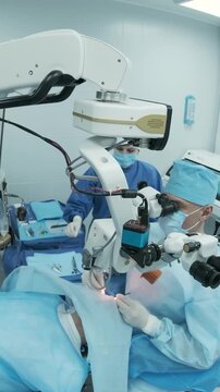 Professional ophthalmologist performing cataract removal and intraocular lens (IOL) implantation under a surgical microscope in an operating room.