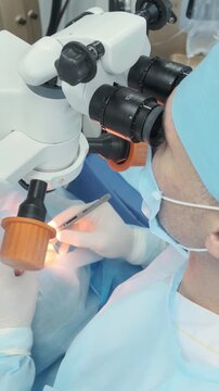 Professional ophthalmologist performing cataract removal and intraocular lens (IOL) implantation under a surgical microscope in an operating room.