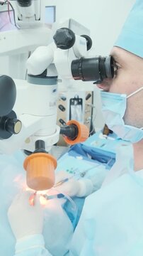 Professional ophthalmologist performing cataract removal and intraocular lens (IOL) implantation under a surgical microscope in an operating room.