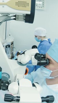 Professional ophthalmologist performing cataract removal and intraocular lens (IOL) implantation under a surgical microscope in an operating room.