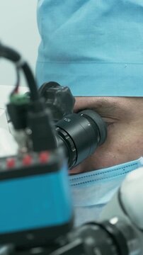 Professional ophthalmologist performing cataract removal and intraocular lens (IOL) implantation under a surgical microscope in an operating room.