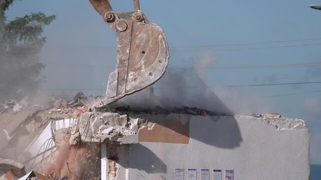 A crane demolishing a multi-story building in sunny weather.