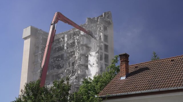 A crane demolishing a multi-story building in sunny weather.