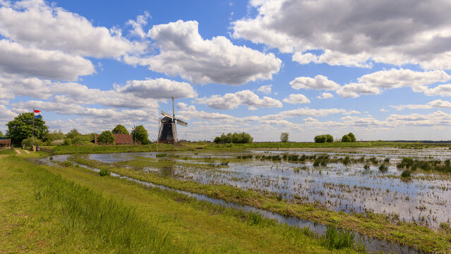 Traditional Dutch landscape with blue sky, clouds, floodplain polder and a classical Dutch windmill on a summer's day at the Onnerlanden, Onnen, Groningen, the Netherlands