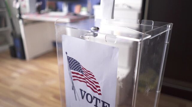 Putting ballot paper into transparent box at polling station for US elections
