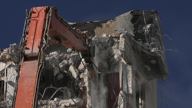 A crane demolishing a multi-story building in sunny weather.