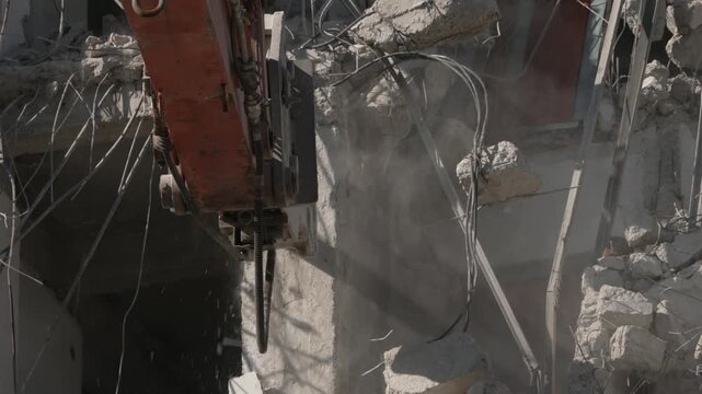 A crane demolishing a multi-story building in sunny weather.