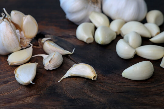 Garlic cloves in a bowl with peeled garlic on wooden background