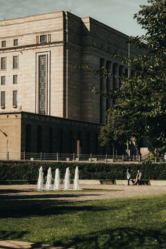 View of the Parliament House with a fountain in the foreground and people sitting on a bench in Helsinki, Uusimaa, Finland.
