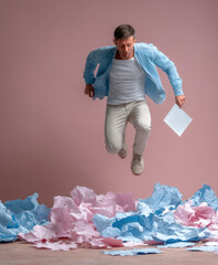 Obraz premium Man jumping over pile of crumpled paper, holding document, wearing casual blue shirt, energetic mood