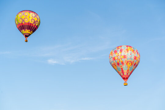 View of two colorful hot air balloons floating against a clear blue sky in Valmiera, Latvija.