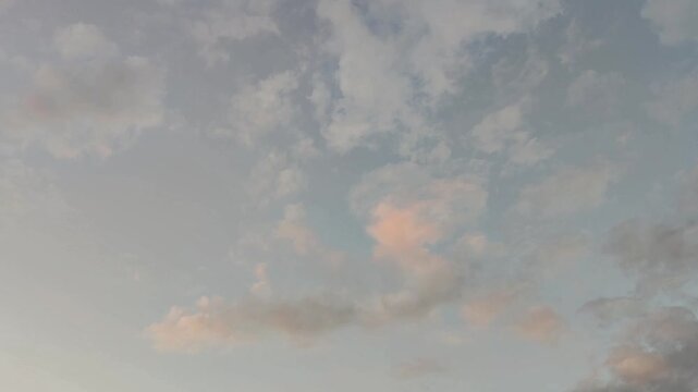 Pink cirrocumulus clouds moving in the sky at dusk