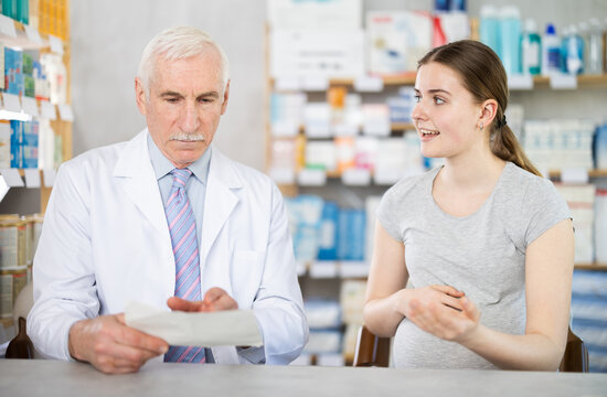 Experienced male pharmacist discussing doctor prescription with girl