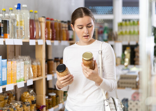 Woman carefully chooses canned beans and lentils