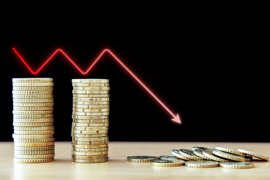 Stacked euro coins and collapsed money with red downward arrow on black background, economic recession financial crisis and loss concept
