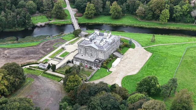 Aerial drone view of historic Westport House surrounded by landscaped parkland, mature woodland and green lawns in Westport, County Mayo, Ireland. The estate is bordered by a scenic waterway and