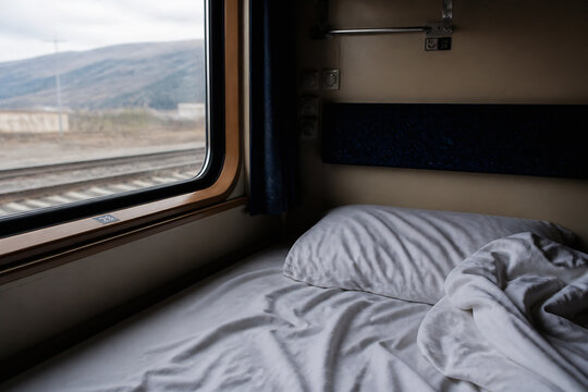 A view from a train window looking out at a landscape while inside a sleeping compartment.
