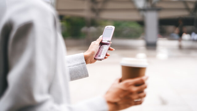 Close up Gen Z young asian businesswoman hand using pink flip phone youth culture digital device