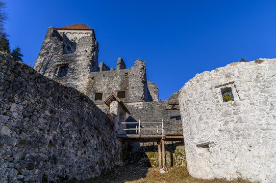 Romanesque keep of Kamen Castle above the lower ward walls and a wooden footbridge, castle ruin, Begunje, Slovenia