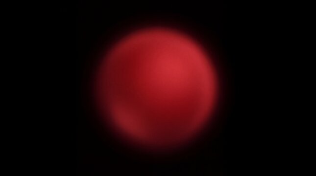 Glowing red orb isolated on solid black background creating minimalist artistic abstract photography style with vibrant crimson lighting effects and smooth rounded shapes inside