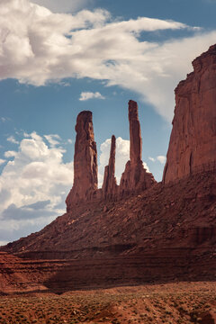 Oljato-Monument Valley, Arizona, United States - 05 September 2018: View of the Three Sisters rock formation, featuring towering red sandstone spires against a blue sky with clouds.