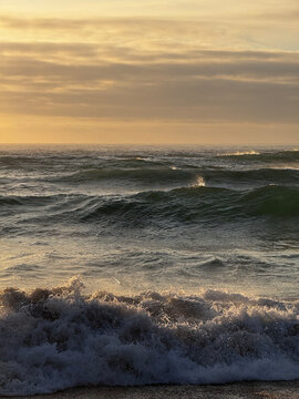 Breaking ocean waves with sunlit sea spray at golden hour
