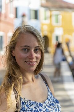 Portrait of a young woman in front of a red wall, looking into the camera, Burano Island, Venice, Veneto, Italy