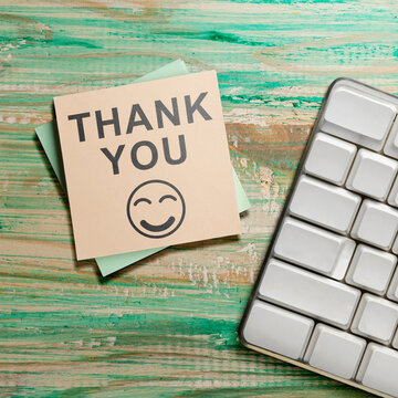Thank you note on a rustic green wooden background next to a modern keyboard. Thank You Message