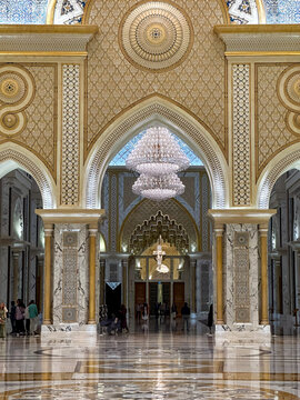 Abu Dhabi, United Arab Emirates - 14 October 2023: View of the opulent Qasr Al Watan Presidential Palace interior, featuring intricate golden patterns, marble columns, and a crystal chandelier.