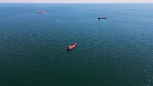 Aerial view of cargo ships and tankers anchored in open calm blue sea waters