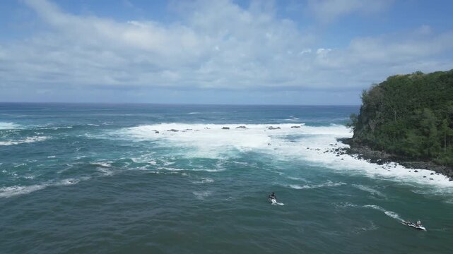 Aerial view backing up from the waves and water in a Maui bay as two jetskis rest in the water