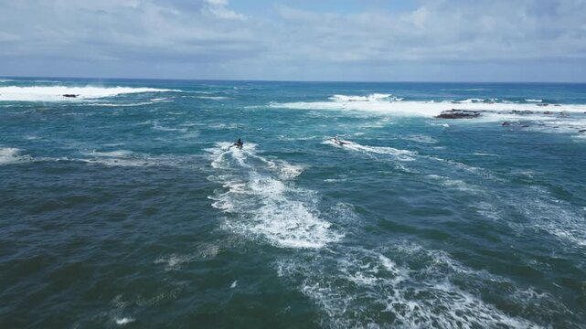 Aerial view of two jetskis driving out into the water against the waves in Maui, Hawaii