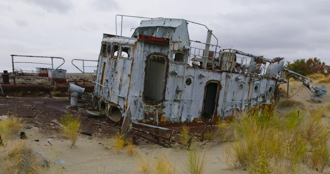 An abandoned rusted ship sits on desert sand in the Aral Sea.