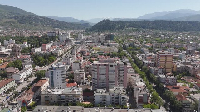 Panoramic aerial view of the city of Elbasan in Albania. Drone flying over the urban landscape with buildings, streets, and mountains