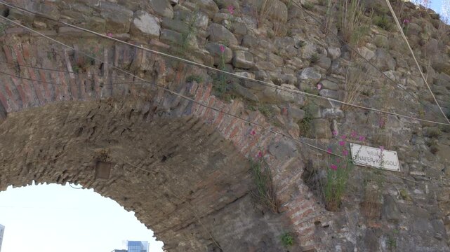 Ancient stone and brick archway, a remnant of the old city walls, decorated with flowers in the historic center of Elbasan, Albania. tilt up shot