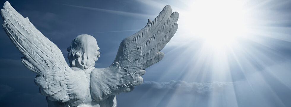Guardian angel facing the radiant light of heaven, symbolic image of hope, faith, salvation and the journey of the soul toward eternity. Copy space for text or design.
