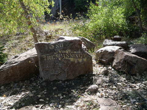 Weathered No Trespassing Sign on Rock Near Railroad in Colorado Mountains