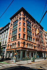 Corner brick building with arched windows and exterior stairs. A salmon colored facade rises above a street corner in New York City, with metal stairs and traffic lights. © Vadim