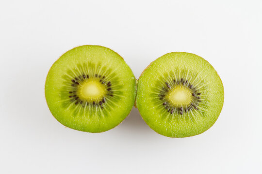 Two sliced fresh kiwi halves with green flesh, black seeds and white core, placed on a plain white background.