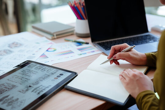 Creative designer reviewing color palettes, architectural concepts, and visual plans on a computer in a modern workspace.
