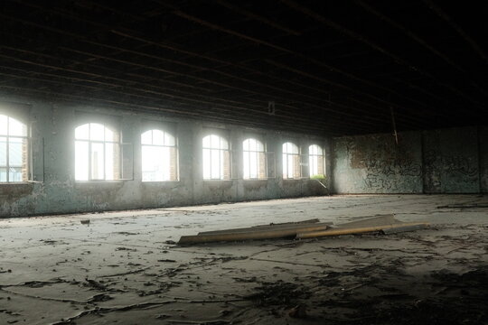 Leipzig, Saxony, Germany - 15 September 2026: View of an abandoned industrial interior with arched windows, peeling walls, graffiti, and debris scattered across the floor.