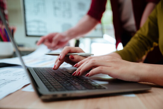 Creative designer reviewing color palettes, architectural concepts, and visual plans on a computer in a modern workspace.