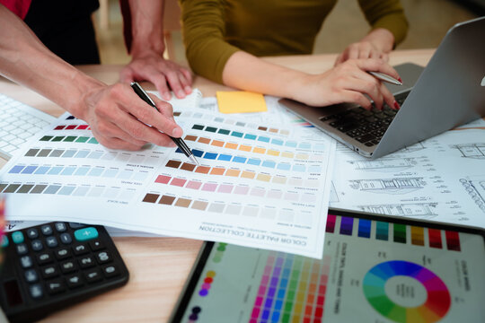 Creative designer reviewing color palettes, architectural concepts, and visual plans on a computer in a modern workspace.