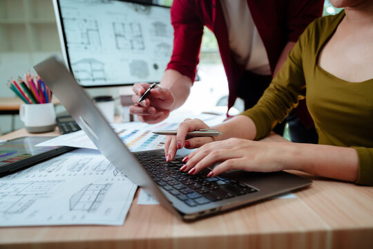 Creative designer reviewing color palettes, architectural concepts, and visual plans on a computer in a modern workspace.